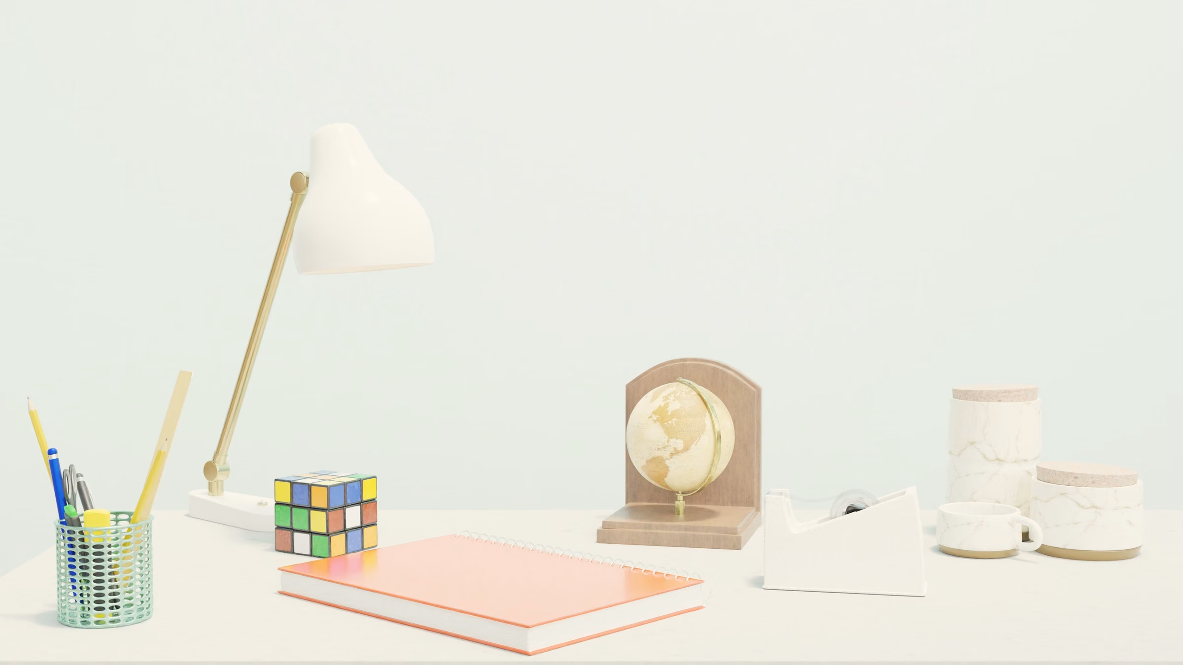 Brass-and-white desk lamp on a pale mint desk beside stationery